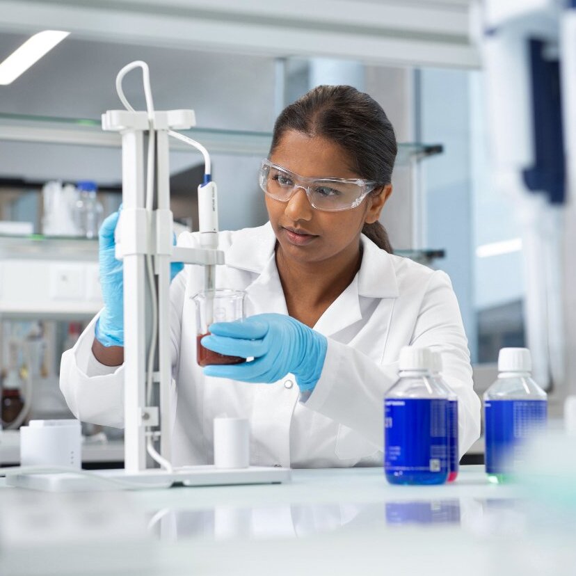 .Scientist holding test tubes in busy laboratory setting.
