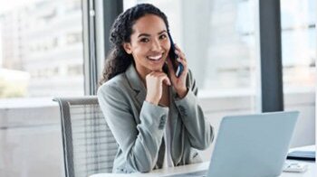 Woman on phone in front of laptop Woman on phone in front of laptop