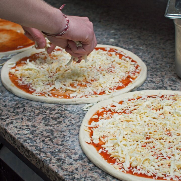 Adding sauce and toppings to pizza in ready-to-eat food production